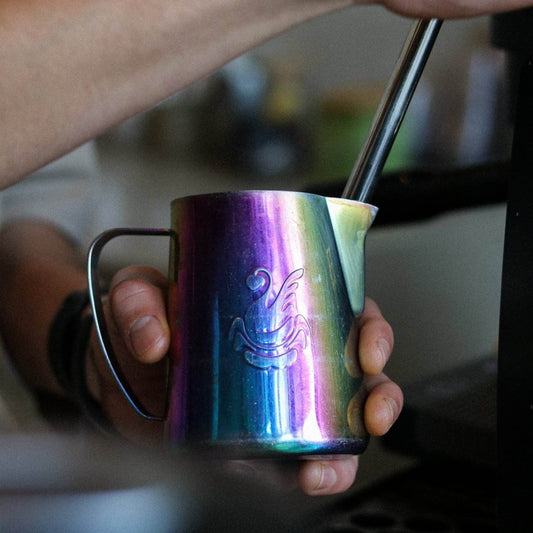 Barista steaming milk to create microfoam during Harvester Latte Art Class, focusing on milk texture and temperature control